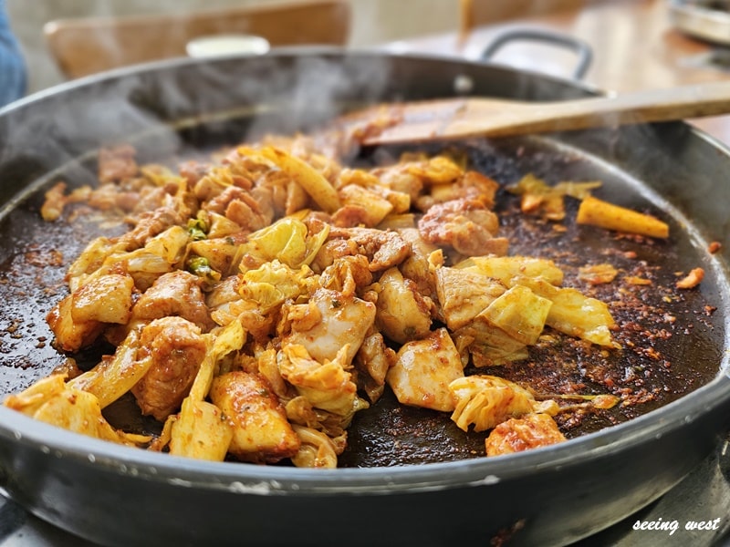 韓國鐵板辣炒雞，配椰菜、年糕等配料，香氣四溢。