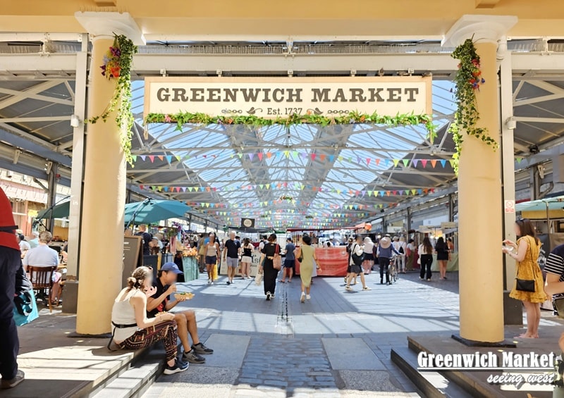 Greenwich Market 主入口人流熱鬧，陽光下懸掛彩旗裝飾